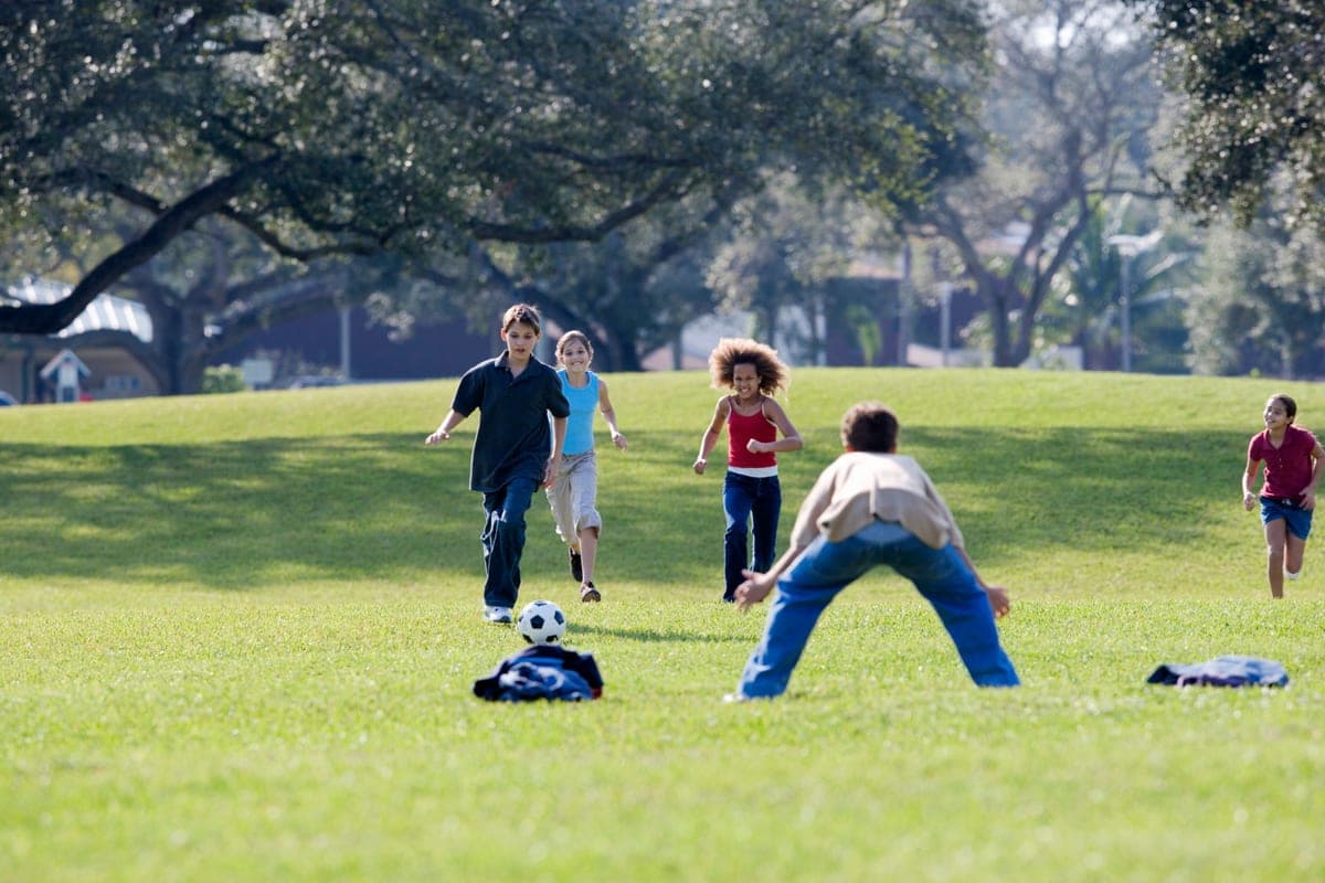 Children running across an open grass field
