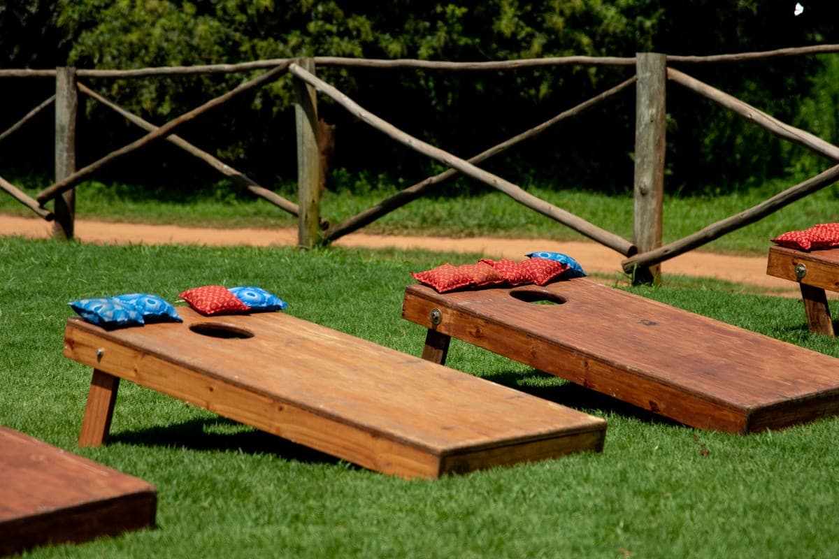 A bean bag in flight toward a target board on a lawn