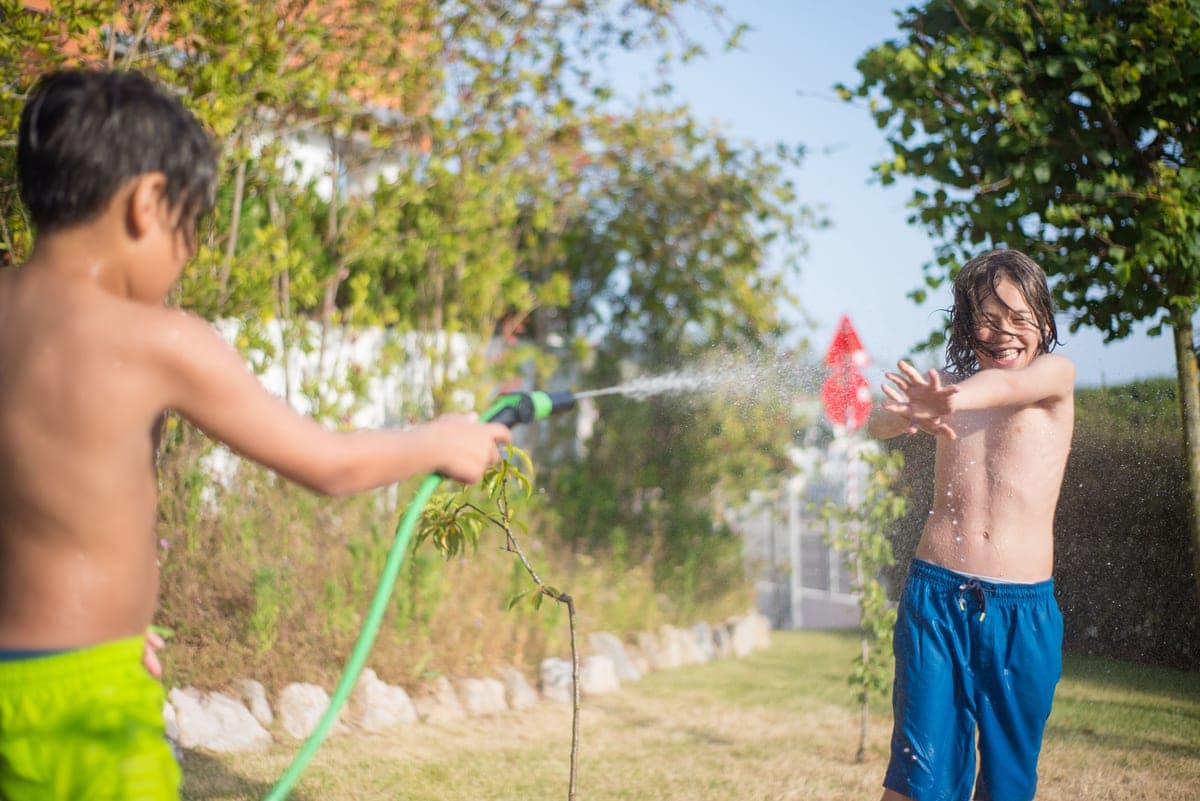 Children running through a garden sprinkler